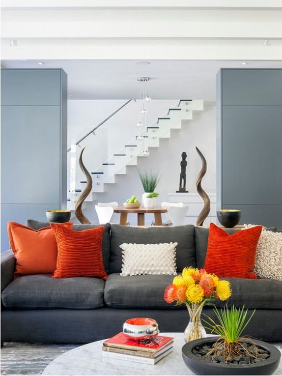 серый диван и оранжевые подушки